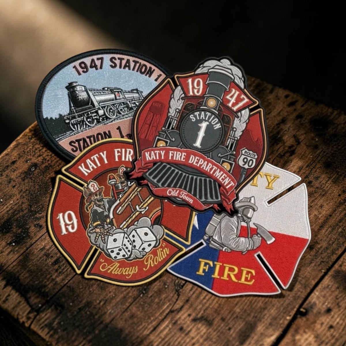Fire department embroidered patches displayed on a rustic wooden surface. The patches feature vintage fire department and train designs with red, black, white, blue, and gold details.slider_item_9rRtUF